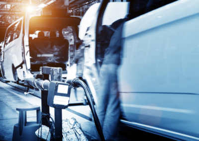 A busy automotive assembly line with white vehicles in motion, showcasing machinery and tools in a factory setting.