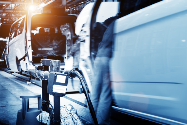 A busy automotive assembly line with white vehicles in motion, showcasing machinery and tools in a factory setting.